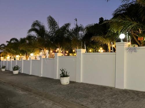 a white fence with potted plants and palm trees at The Joneses in Plettenberg Bay