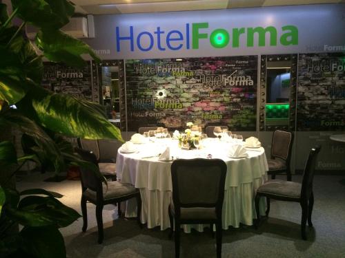a table in a restaurant with chairs and a hotel formula sign at Hotel Forma in Piła