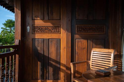 a table and a chair on a porch with a wooden door at Uma Sebatu Villa Ubud in Tegalalang