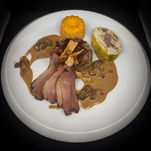 a white plate of food with meat and sauce at Le Manoir Au Lac in Gérardmer