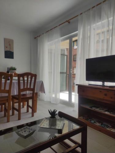 uma sala de estar com uma televisão de ecrã plano e uma mesa em APARTAMENTO TERESA em Calpe