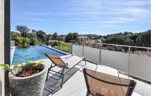 a balcony with a table and chairs and a swimming pool at Beautiful Home In Cavalaire-Sur-Mer in Cavalaire-sur-Mer