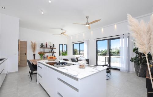 a kitchen and living room with white cabinets and a table at Beautiful Home In Cavalaire-Sur-Mer in Cavalaire-sur-Mer
