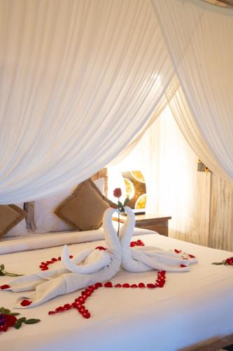 two swans are sitting on a bed with red roses at Uma Sebatu Villa Ubud in Tegalalang