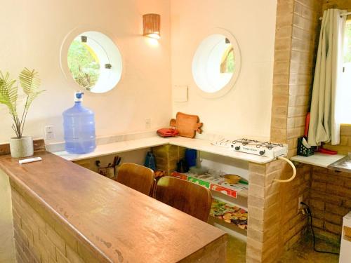 a kitchen with a counter with a sink and two windows at Chalé Nova Terra in Imbassai