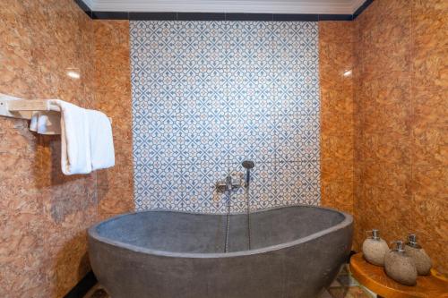 a bath tub in a bathroom with a stone wall at Uma Sebatu Villa Ubud in Tegalalang
