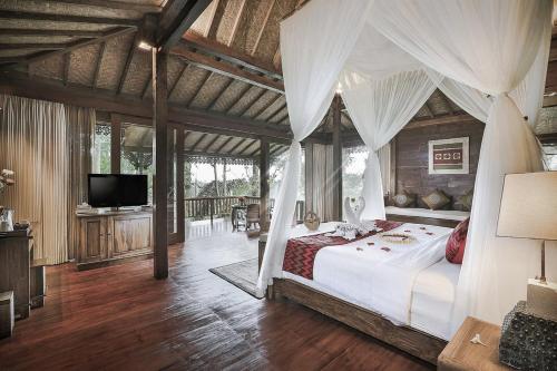 a bedroom with a canopy bed and a television at Sunia Jungle Ubud View by EPS in Ubud