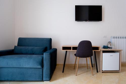 a living room with a blue chair and a desk at Leone Suites Toledo in Naples