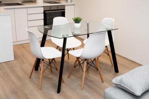 a glass dining table and four white chairs in a kitchen at Ring Inn Apartments in Obrenovac