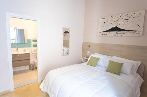 ein weißes Schlafzimmer mit einem weißen Bett und einem Badezimmer in der Unterkunft Leone Suites Toledo in Neapel