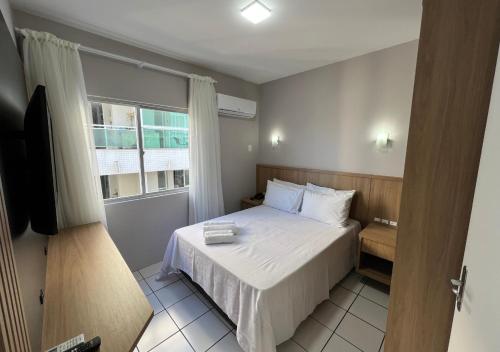 a small bedroom with a bed and a window at Ilha Forte Praia Hotel in Florianópolis