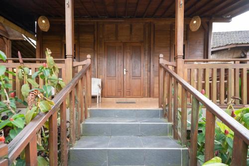 a wooden house with stairs leading to a wooden door at Uma Sebatu Villa Ubud in Tegalalang