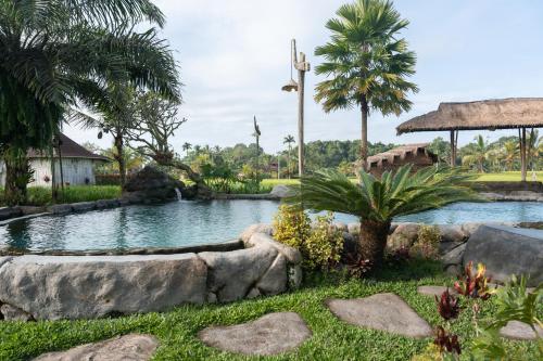 a pond in the middle of a yard with palm trees at Uma Sebatu Villa Ubud in Tegalalang