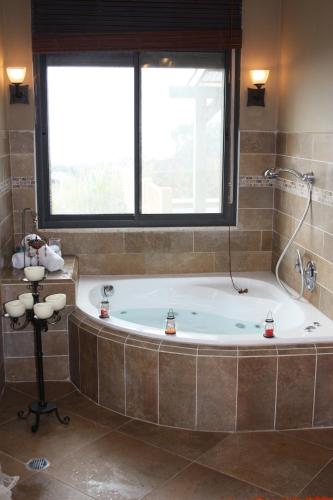 a large bathroom with a tub and a window at Zimmerke in Bruchim Qela' Alon