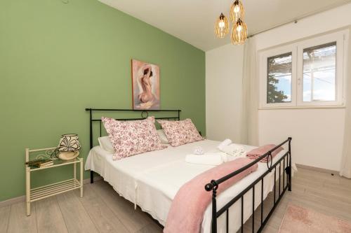 una camera da letto con un letto con cuscini rosa e bianchi di Apartments Villa White House a Omiš (Almissa)