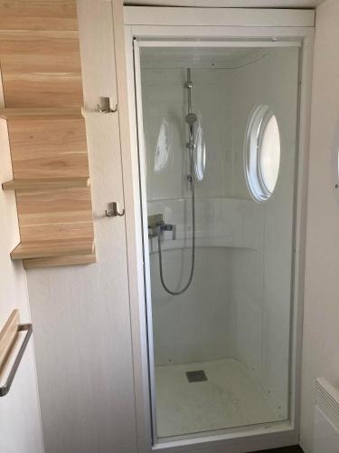 une douche avec une porte vitrée dans une salle de bain dans l'établissement Camping 5* - Biscarosse Lac - MobilHome 2 chambres - 4 personnes, à Biscarrosse