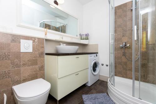 ein Badezimmer mit einem WC, einem Waschbecken und einer Waschmaschine in der Unterkunft Apartments Villa White House in Omiš