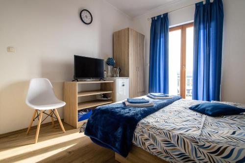 una camera con letto, TV e tende blu di Rooms Bačić a Neum