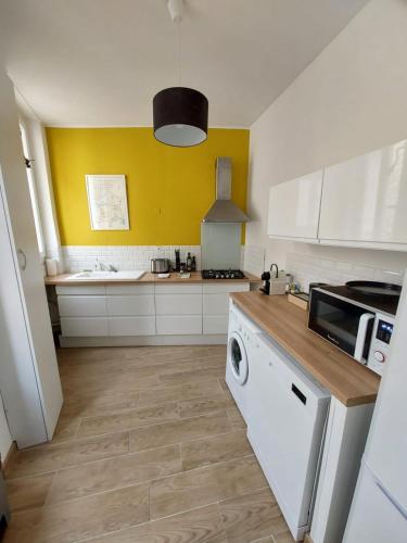 une cuisine avec des armoires blanches et une machine à laver dans l'établissement Le Mistralet, à Salon-de-Provence