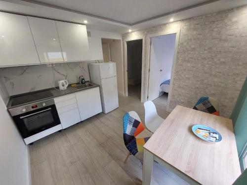 una cocina con armarios blancos y una mesa con sillas. en SDH apartments, en Alicante