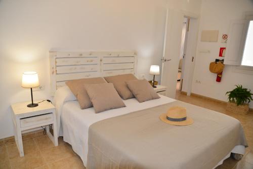 a bedroom with a white bed with a hat on it at Casa Can Relax in Es Pujols
