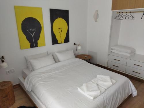a bedroom with a white bed with two pictures on the wall at Minimal apartment by the beach in Korinthos