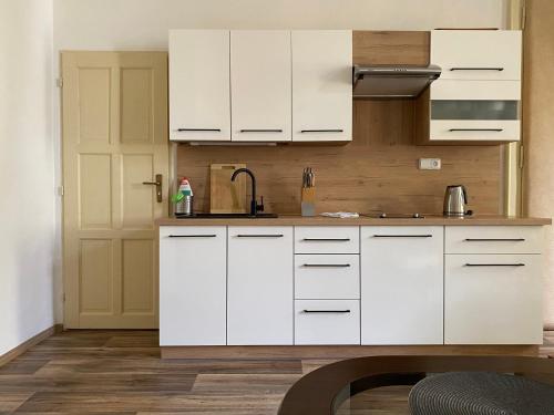 a white kitchen with white cabinets and a door at Apartmán Kaiser in Prague