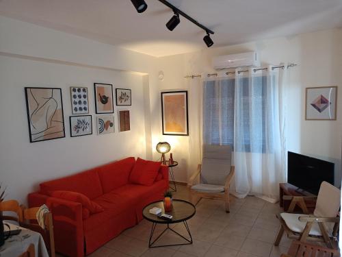 a living room with a red couch and a tv at Sea view Pine house in Makry Gialos