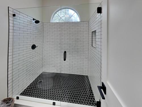 Un baño con ducha con azulejos blancos y negros. en Wood Beach Retreat, en Santa Rosa Beach