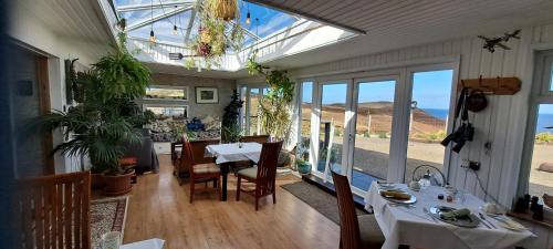 - une salle à manger avec une table, des chaises et des fenêtres dans l'établissement Salmon Landings, à Strathy Point