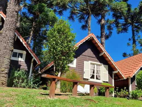 a house with a pitched roof and a tree at Pousada Caliandra Da Serra in Canela