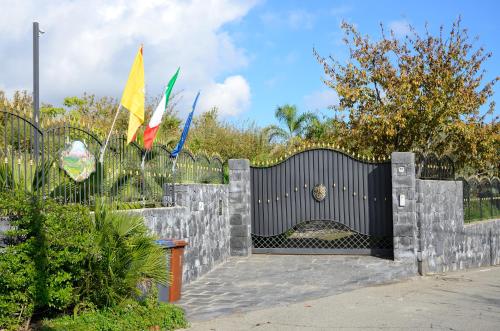 a black gate with a stone fence and flags at B&B Dimora dell' Etna in Milo