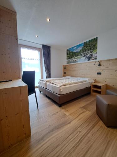 a bedroom with a bed and a desk and a chair at Bait da Pemont in Livigno