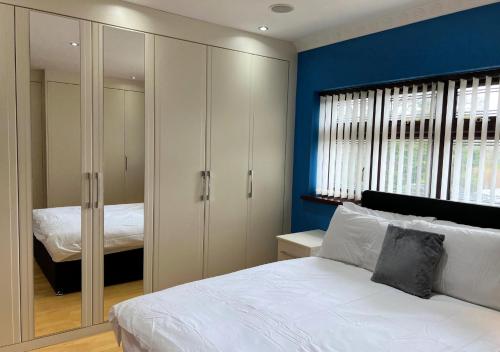 Luxury Canterbury Holiday Home Sleeps Ten Wifi في كانتربيري: غرفة نوم بسرير ابيض وجدار ازرق