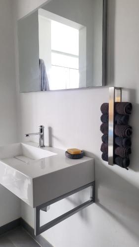a white bathroom with a sink and a mirror at Apartman s bazénem a saunou in Kadaň