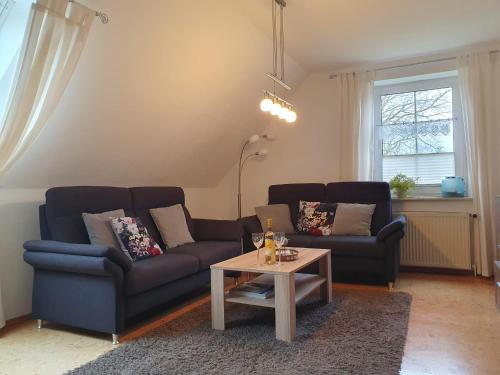 een woonkamer met 2 banken en een salontafel bij Ostfriesland Apartements -FeWo- in Upgant-Schott