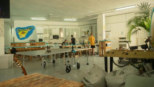 un groupe de personnes dans une pièce avec des tables dans l'établissement Medano Nest Hostel, à El Médano