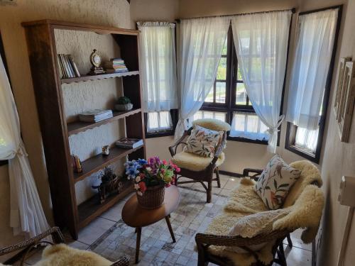 a living room with two chairs and two windows at Pousada Caliandra Da Serra in Canela