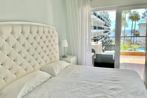 um quarto com uma grande cama branca e uma varanda em MI CAPRICHO 9A BEACHFRONT- Apartment with sea view - Costa del Sol em Sitio de Calahonda