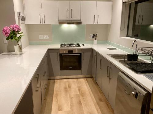 a kitchen with white cabinets and a stove and a sink at Tonquani - Knysna (est. 2022) in Knysna