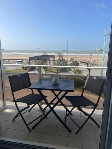 a table and chairs on a balcony with a view of the beach at Appartement T2 vue mer les pieds dans l'eau avec parking privé in Saint-Jean-de-Monts