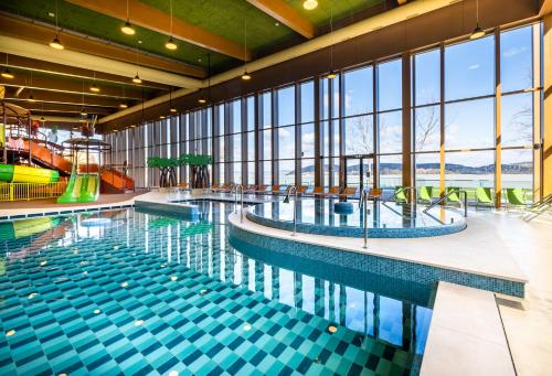 a swimming pool in a building with windows at Mövenpick Balaland Resort Lake Balaton in Szántód