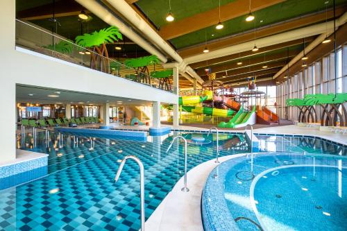 a swimming pool with a slide in a building at Mövenpick Balaland Resort Lake Balaton in Szántód