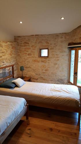 two beds in a room with a brick wall at Le Marais in Chasseneuil-sur-Bonnieure