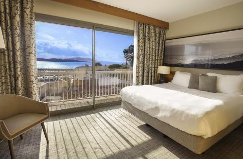 a hotel room with a bed and a large window at Thalazur Bandol Ile Rousse - H&ocirc;tel & Spa in Bandol