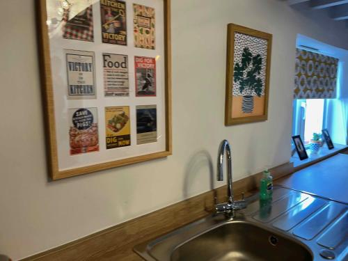 a sink in a kitchen with posters on the wall at The North Wales Gathering - Hot Tub & Sleeps Up To 16 in St Asaph