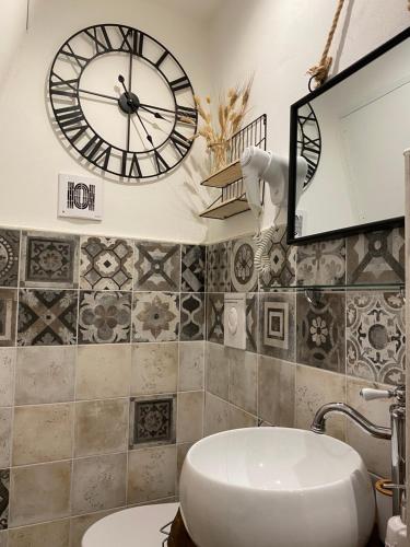 baño con reloj en la pared y lavabo en Domus Klara, en Turi