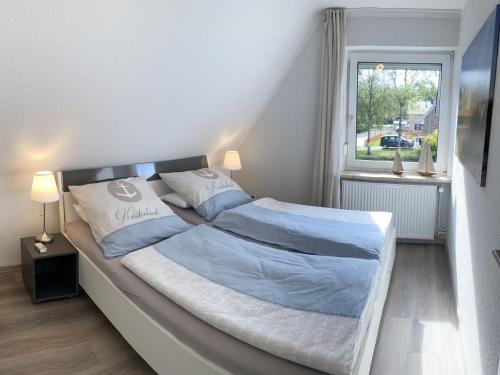 una camera da letto con un letto con lenzuola blu e una finestra di Ankerplatz10 a Varel