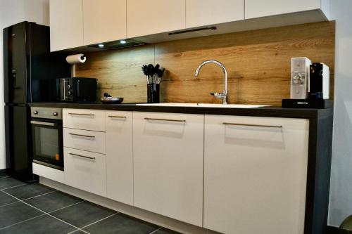 a kitchen with white cabinets and a sink at Le Cosy in Crest