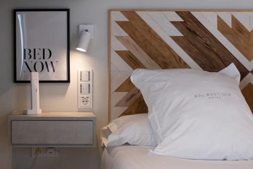 a bed with a wooden headboard and a white pillow at Hotel Sol Boutique in Santander